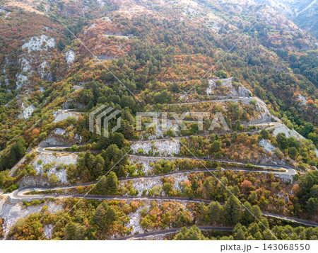 Lovcen Serpentine Montenegro follows series of tight hairpin turns on wooded mountain slope. Serpentine road stands out against autumn foliage, rocky cliffs, and calm scenic atmosphere. Lovcen Serpentine Montenegro follows series of tight hairpin turns on wooded mountain slope. Serpentine road stands out against autumn foliage, rocky cliffs, and calm scenic atmosphere. 143068550