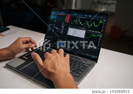 Person trading online, monitoring stock market charts and financial data on laptop computer, analyzing investments and making decisions for wealth management using digital technology at home. Person trading online, monitoring stock market charts and financial data on laptop computer, analyzing investments and making decisions for wealth management using digital technology at home. 143069055