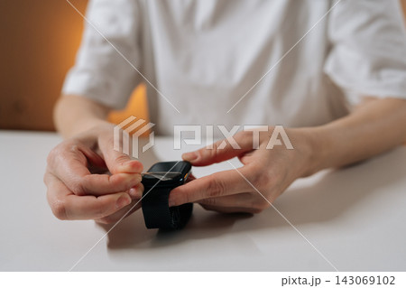 Cropped shot of unrecognizable woman using specialized tool to remove old protective film from screen of modern smartwatch, illustrating maintenance and protection of personal wearable technology. Cropped shot of unrecognizable woman using specialized tool to remove old protective film from screen of modern smartwatch, illustrating maintenance and protection of personal wearable technology. 143069102