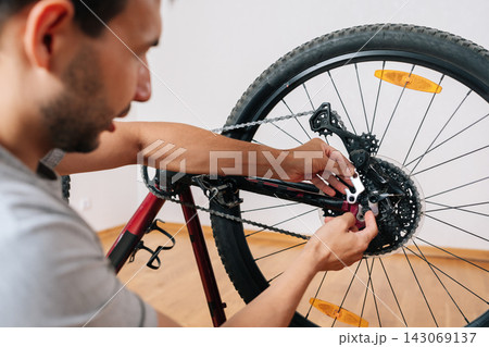DIY bicycle repair concept. Man hands working on bike transmission. Close-up view with shallow depth of field. Hobby and active lifestyle maintenance in home workshop. 143069137
