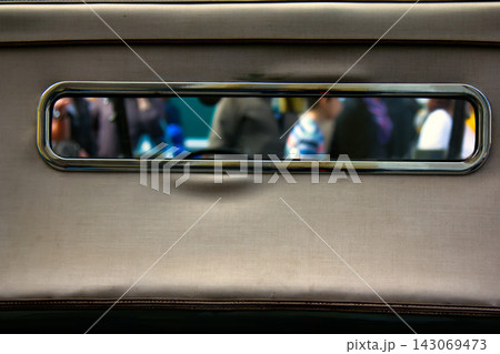 View of crowd of passers-by through rear view window of vintage car 143069473