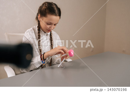Cute 10s young girl with braided hair holding heart shaped candy, embodying sweetness and simple happiness during her childhood years, perfect for themes of joy and innocence. 143070198