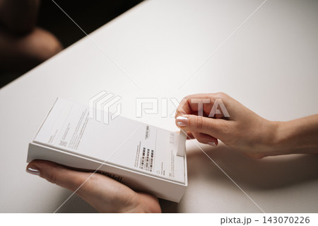 Ufa, Russia - 17 August 2025. Close-up female hands opening apple iPhone 16 Pro retail box, revealing new device inside, on white table, symbolizing fresh start and technological advancement. 143070226