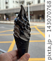 Black charcoal soft serve ice cream cone held in hand on Hong Kong street 143070768