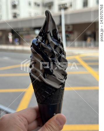 Black charcoal soft serve ice cream cone held in hand on Hong Kong street 143070768