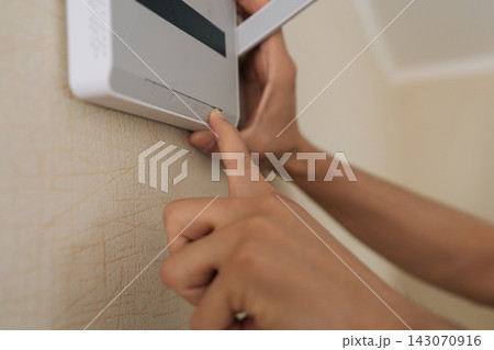 Close-up shot showing person finger pressing button on white wireless router mounted on wall. Shallow depth of field focuses on technology connectivity. Neutral colors create modern, everyday feel. Close-up shot showing person finger pressing button on white wireless router mounted on wall. Shallow depth of field focuses on technology connectivity. Neutral colors create modern, everyday feel. 143070916