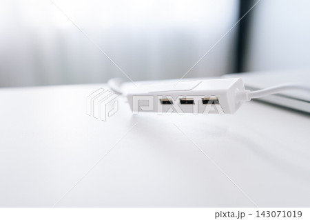 Close-up of modern white USB hub splitter on minimalist desk. Bright, high key lighting with shallow depth of field. Clean technology concept for office, workspace, or connectivity. 143071019