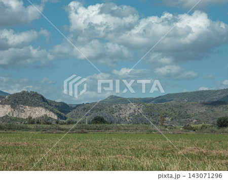 Scenic rural landscape with rice paddies and mountains under a blue sky filled with clouds Scenic rural landscape with rice paddies and mountains under a blue sky filled with clouds 143071296