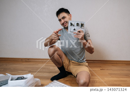 Smiling man holding blister pack of furniture parts and allen key, pointing finger towards camera, conveying sense of invitation, readiness, successful diy home improvement. Smiling man holding blister pack of furniture parts and allen key, pointing finger towards camera, conveying sense of invitation, readiness, successful diy home improvement. 143071324