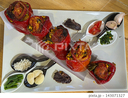 Gourmet dish of traditional Valencian stuffed peppers served with raw ingredients on a decorative platter 143071327