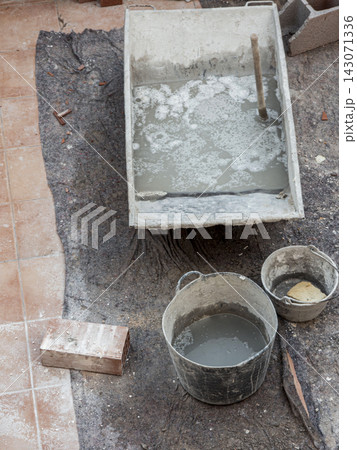 Close view of a plastic trough with concrete mix and buckets on a construction site Close view of a plastic trough with concrete mix and buckets on a construction site 143071336