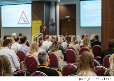 Conference audience facing two presentation screens Conference audience facing two presentation screens 143071357