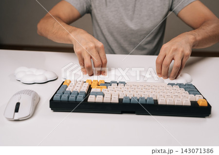 Close-up of man placing cloud-shaped wrist rest for ergonomic comfort while using mechanical keyboard and wireless mouse on clean white desk, highlighting modern desk setup for work or gaming. Close-up of man placing cloud-shaped wrist rest for ergonomic comfort while using mechanical keyboard and wireless mouse on clean white desk, highlighting modern desk setup for work or gaming. 143071386