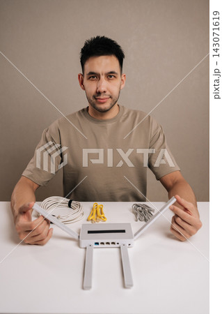 Bearded handsome man working with wireless router and various cables, setting up home network connectivity, troubleshooting internet solutions for seamless digital usage. 143071619