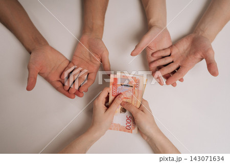 Top view of hands receiving money, person distributing Russian rubles from a stack of bank notes, visualizing financial support, salary, income distribution, or debt repayment concepts. Top view of hands receiving money, person distributing Russian rubles from a stack of bank notes, visualizing financial support, salary, income distribution, or debt repayment concepts. 143071634