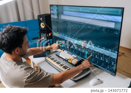 Rear view of sound engineer male creating new music in home studio, arranging tracks and mixing audio levels with midi keyboard and software on a large display, showcasing modern music production. Rear view of sound engineer male creating new music in home studio, arranging tracks and mixing audio levels with midi keyboard and software on a large display, showcasing modern music production. 143071772