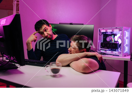 Two male developers experiencing stress and frustration from coding issues and tech burnout working in modern office with vibrant neon lighting. Two male developers experiencing stress and frustration from coding issues and tech burnout working in modern office with vibrant neon lighting. 143071849