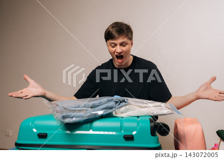 Emotional traveler packing clothes into a teal suitcase, using vacuum compression bags to save space, expressing astonishment at the effective packing solution before a trip. 143072005