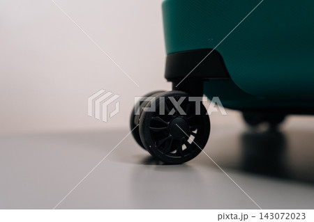 Teal travel suitcase resting on its black wheels, representing concepts of travel, departure, arrival, vacation, business journey, tourism, and individual mobility. 143072023