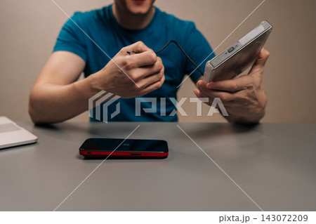 Person connecting a usb cable into a portable external optical disc drive for data transfer and media playback on modern laptops. Person connecting a usb cable into a portable external optical disc drive for data transfer and media playback on modern laptops. 143072209