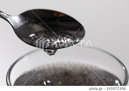 Macro close-up of soaked chia seeds swelling into a gel in water with spoon Macro close-up of soaked chia seeds swelling into a gel in water with spoon 143072306