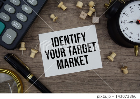 Identify Your Target Market text written on notepad with pen, alarm clock, magnifying glass and calculator on wooden background 143072866