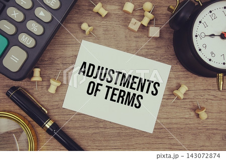 Adjustments Of Terms text written on notepad with pen, alarm clock, magnifying glass and calculator on wooden background 143072874
