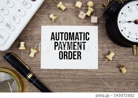 Automatic Payment Order text written on notepad with pen, alarm clock, magnifying glass and calculator on wooden background 143072882