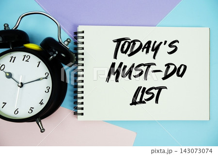Today's Must-Do List text written on notepad with alarm clock flat lay on multicolor pastel background Today's Must-Do List text written on notepad with alarm clock flat lay on multicolor pastel background 143073074