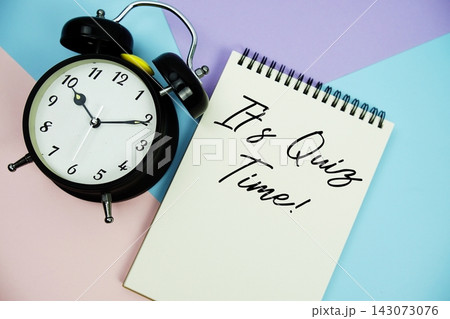 It's Quiz Time! text written on notepad with alarm clock flat lay on multicolor pastel background 143073076