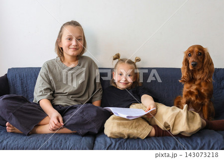 Indoor portrait of children playing dog sitting on sofa at home. Kids and red cocker spaniel pet 143073218