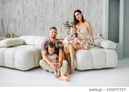 Parents with Two Kids Posing near Sofa Parents with Two Kids Posing near Sofa 143073357
