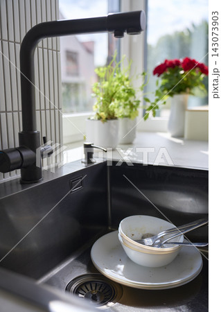 Used bowl, plate and cutlery with food residue are left in kitchen sink Used bowl, plate and cutlery with food residue are left in kitchen sink 143073903