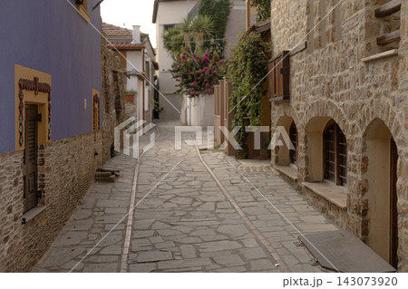 Cobblestone alleyway in Greek village with blue walls and stone buildings Cobblestone alleyway in Greek village with blue walls and stone buildings 143073920