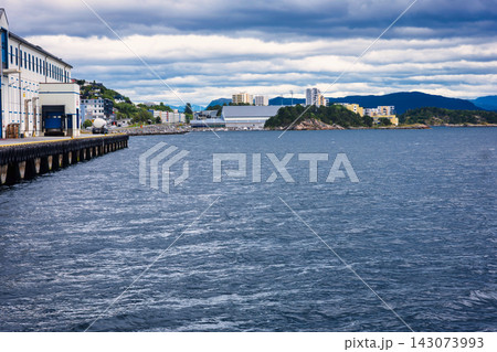 Industrial waterfront with loading dock and residential buildings across bay, Norway 143073993