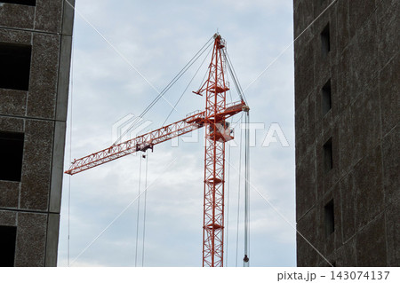 Orange Tower Crane Standing Between Concrete Panel Buildings Orange Tower Crane Standing Between Concrete Panel Buildings 143074137