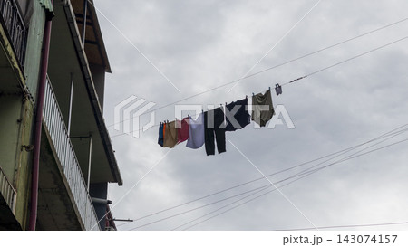 Low angle view of clothes and laundry hanging to dry on a line outside an apartment building. City 143074157