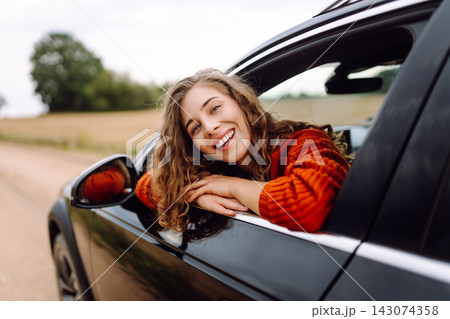 Woman enjoys ride in car with window down on rural road during cloudy day Woman enjoys ride in car with window down on rural road during cloudy day 143074358