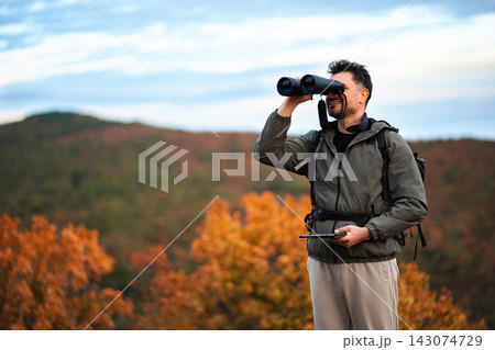 Enjoying the autumn view while observing nature through binoculars Enjoying the autumn view while observing nature through binoculars 143074729