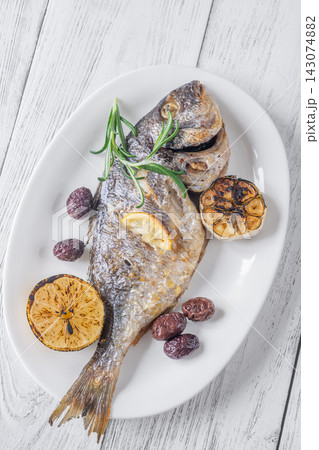 Whole roasted sea bream with lemon rosemary olives and caramelized garlic Mediterranean style Whole roasted sea bream with lemon rosemary olives and caramelized garlic Mediterranean style 143074882