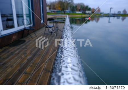 Raindrops on metallic handrail by lakeside deck in Belarus 143075270