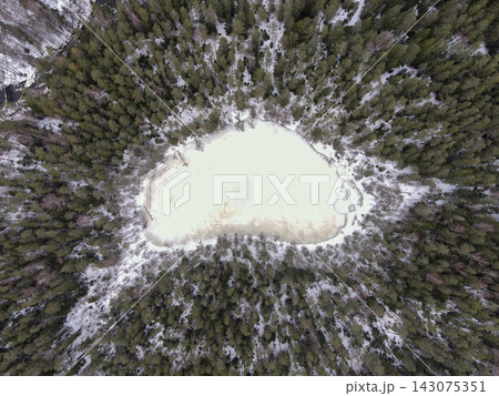 Aerial view of oval ice lake and snowy conifer forest in Belarus Aerial view of oval ice lake and snowy conifer forest in Belarus 143075351