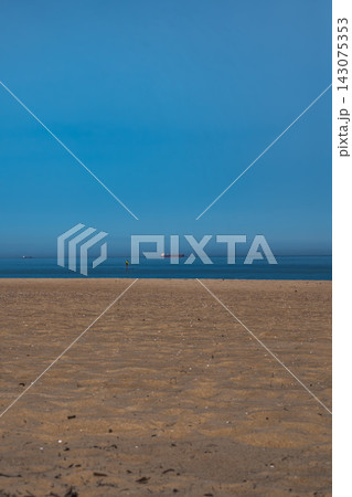 Sandy Baltic shore with red cargo ship, small vessel, and paddleboarder Sandy Baltic shore with red cargo ship, small vessel, and paddleboarder 143075353