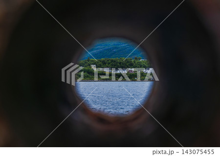 Circular framed view of coastal settlement through stone aperture, Norway fjord Circular framed view of coastal settlement through stone aperture, Norway fjord 143075455