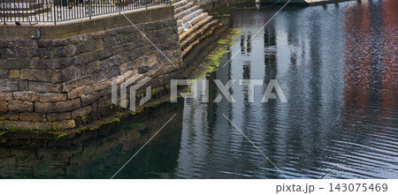 Stone harbor wall with moss growth and water reflections, Norway Stone harbor wall with moss growth and water reflections, Norway 143075469