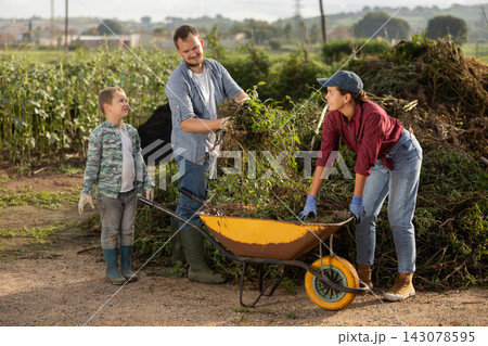 Family of farmers puts branches in a cart Family of farmers puts branches in a cart 143078595