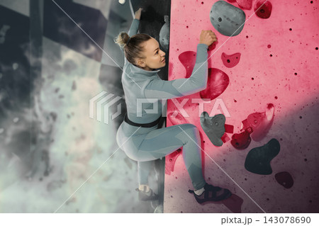 Young woman exercising on wall in climbing gym during bouldering training 143078690