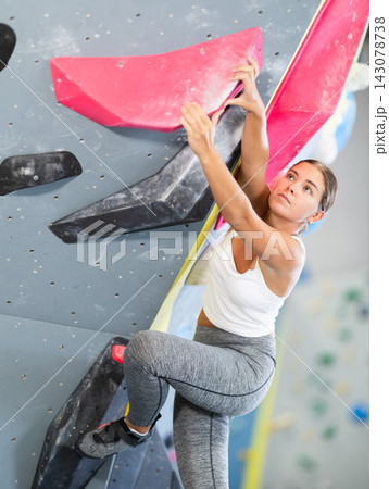 Young woman practicing rock climbing on climbing wall Young woman practicing rock climbing on climbing wall 143078738