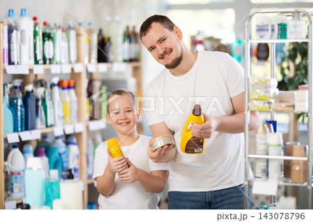 Schoolboy son and dad are choosing wood polish in store 143078796