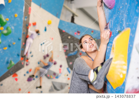 Young girl climbing without ropes and harnesses on bouldering wall Young girl climbing without ropes and harnesses on bouldering wall 143078837